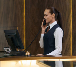 manager uniform booking room by phone while standing counter working 1